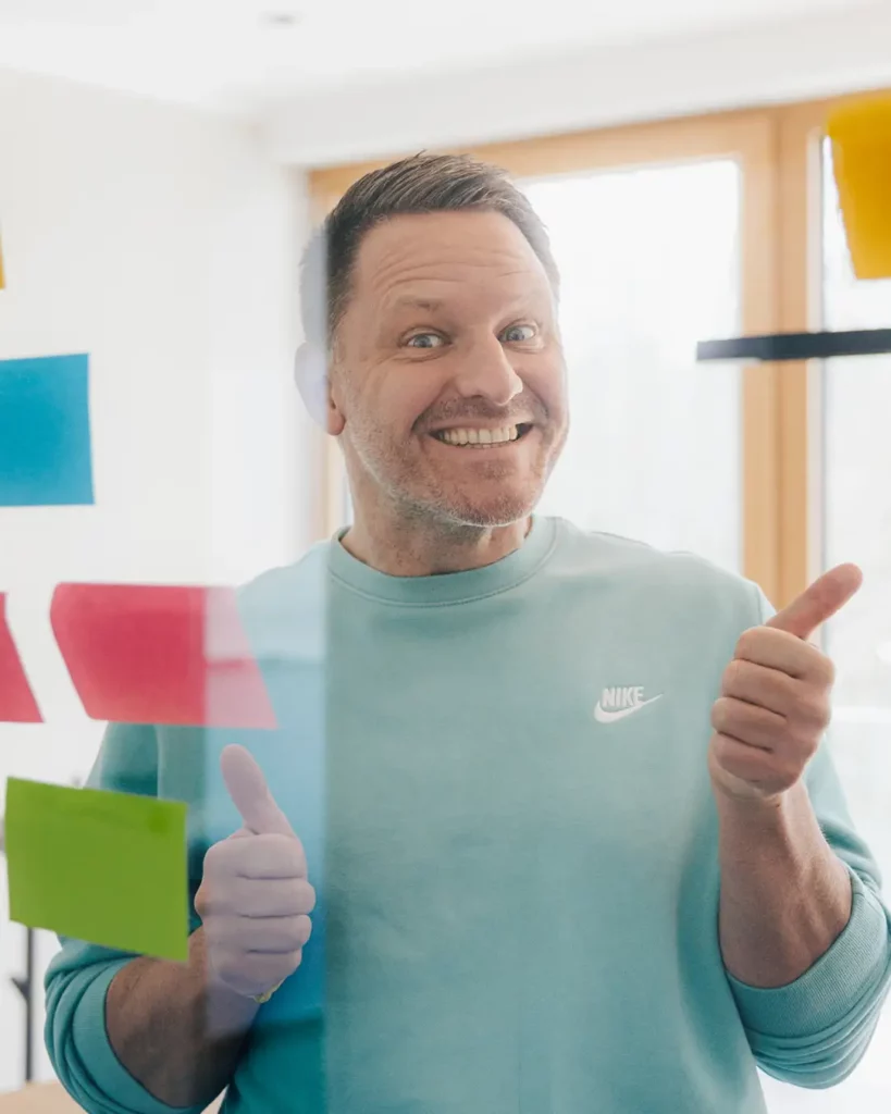 4 Tage Woche in der Werbeagentur Phil ist happy und zeigt mit beiden Händen Daumen nach oben.