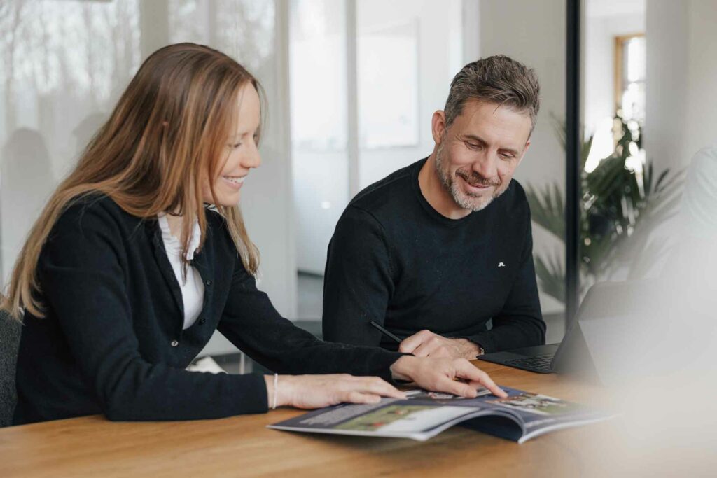 Christoph und Steffi – Sie schauen sich gemeinsam eine Kundenbroschüre an, besprechen Details und entwickeln neue Ideen.